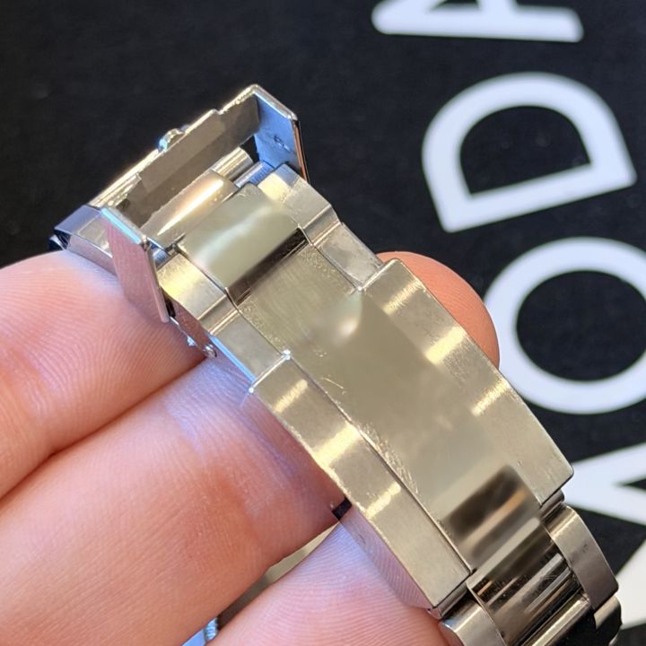 Steel Rolex Oysterlock clasp held in a hand, with its small safety catch flipped up
